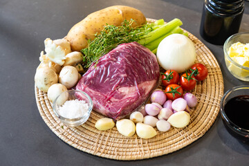 close up to Raw Ingredients for beef steak and mushroom sauce menu on circle wicker plate.