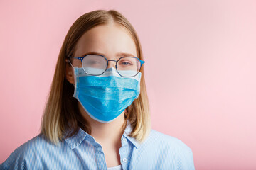 Foggy glasses wearing on woman. Woman portrait in medical protective face mask and eyeglasses wipes blurred foggy misted glasses on pink color background copy space. Covid coronavirus lockdown