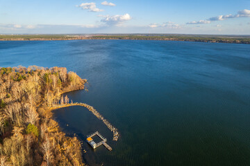 Colorful autumn forest with trees on the shore of a blue lake - top aerial view.