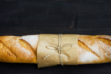 Baguette. Fresh golden baguette on an old wooden table. Close-up. French traditional bread on a dark background. Top view. Copy space. - 467827181