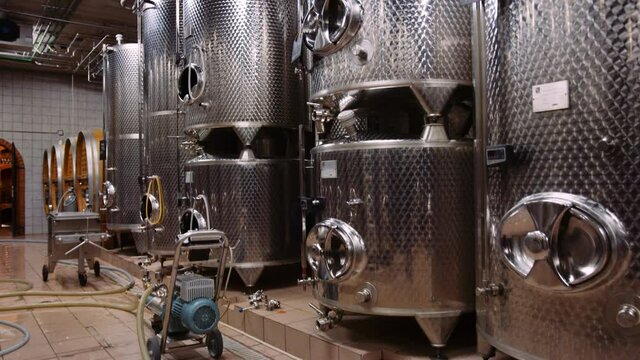 Tilt-up shot reveals big stainless steel vessels used for fermentation of wine