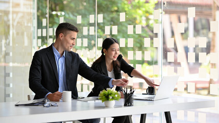 Businesswoman pointing finger on laptop screen to shows the data to her boss
