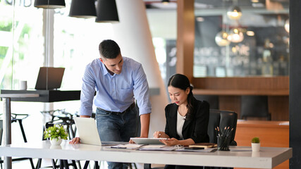 Caucasian businessman mentor training young asian female assistant