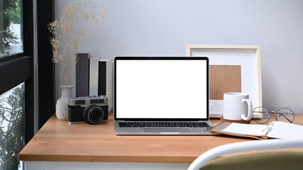 Comfortable workplace with computer laptop, coffee cup and notebook on wooden table.