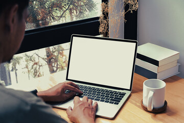 Over shoulder view of young man freelancer working with laptop computer at home.