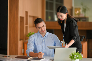 Business female manager shows business informations via tablet.