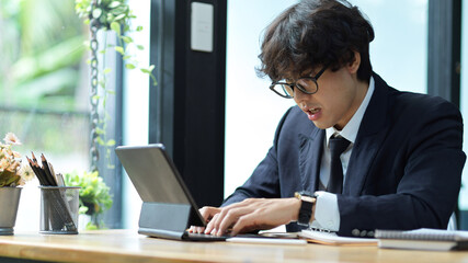 Fototapeta na wymiar Businessman working hard on his project via digital tablet computer