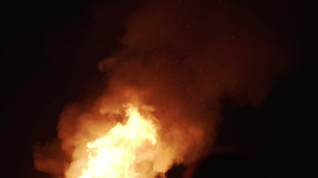 Large groups of people stand in front of huge fire to celebrate guy fawkes day