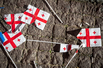 Many teared apart georgian flags on pavement. Crisis in caucasus concept. B&w background banner