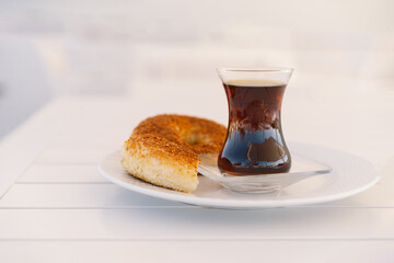 Crispy Turkish traditional bagel, simit with sesame and glass of turkish black tea, turkish breakfast pastry concept. Turkish tea in traditional glass cup. 