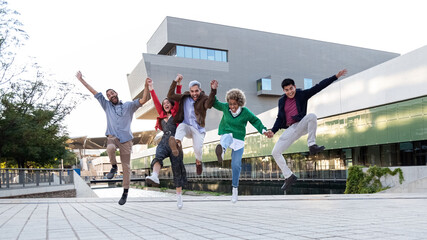 Multiracial group of friends jumping in the air in a city square. Copy space. Horizontal banner image. © Daniel