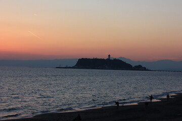 夕暮れの湘南の海。オレンジ色に染まる空と、江の島
