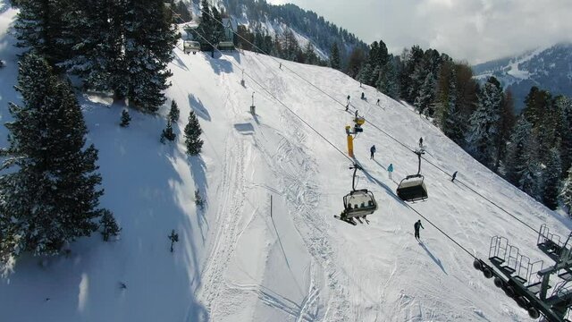Aerial Drone eastablishing shot of a ropeway of Obereggen delivering people towards the peak and some ski riders going down the ski slope