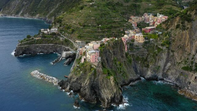 Aerial Panning Built Structures Of Houses On Green Mountain, Drone Flying Over Ocean Water - Cinque Terre, Italy