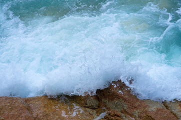Waves crushing into the rocks. Bubble sea waves hit the rocks. (Koh Lipe, Thailand)