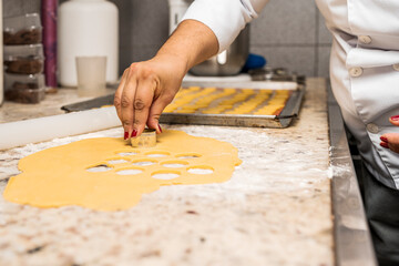 Female chef cutting a pastry dough into slices using a mould in a kitchen