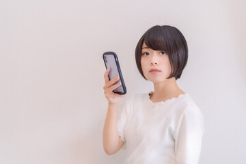 スマホを持ってこちらを見る真顔の女性