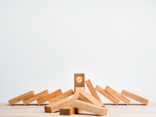 The big wooden block strong with shield security icon symbol standing protects falling domino...