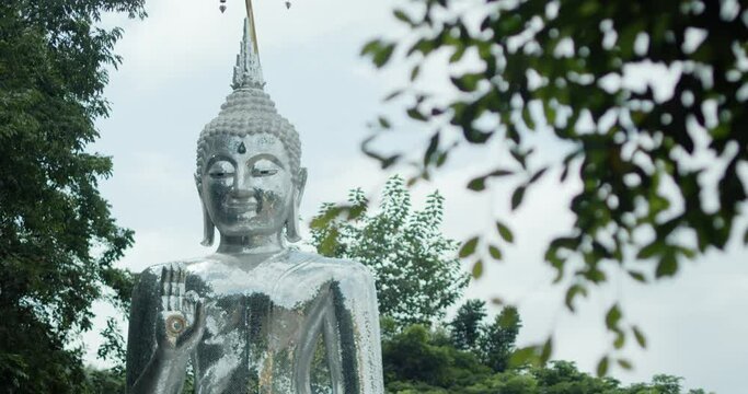 Rack focus and dolly in scene of white Buddha statues in a Buddhist temples in Thailand.
