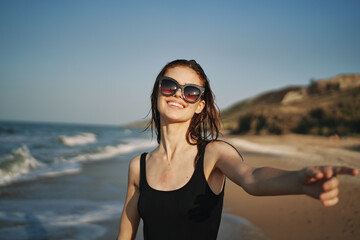cheerful woman in a black swimsuit walking along the beach tropics summer