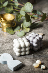 One blue candle shaped as greek goddess and bubble candles on a grey surface and a branch of eucalyptus