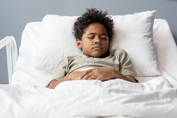Hard sick boy with tubes in his nose sleeping in bed at hospital