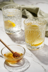 Two glasses with water and lemon, honey in the morning light - breakfast