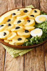 Papa a la Huancaina dish of sliced potatoes with a special sauce close up in the plate on the table. Vertical