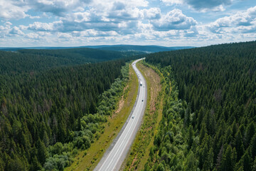 Aerial view of scenic road between green trees with pines on a sunny summer morning. Nature landscape in Siberia, Russia. A road passing through a coniferous forest, aerial shot from a drone.