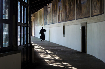 Un frate cammina in un corridoio delSantuario della Verna punto di partenza della Via di Francesco - obrazy, fototapety, plakaty