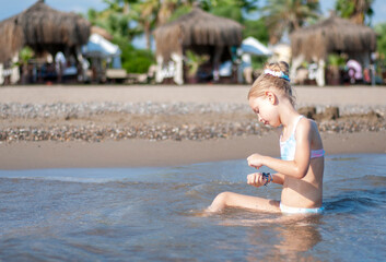 Little girl playing on the beach by the sea