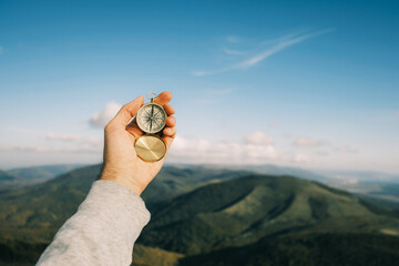 Travel concept. Vintage compass on a background of blue sky and mountains. - obrazy, fototapety, plakaty