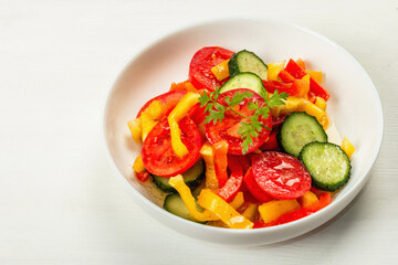 Seasonal fresh vegetable salad with ripe tomatoes, cucumbers, bell peppers