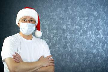 A man in a Santa Claus hat and a medical mask on his face. Christmas and the coronavirus.