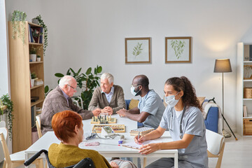 Two doctors in masks talking to senior people about their health and prescribing medicine during their work in nursing home