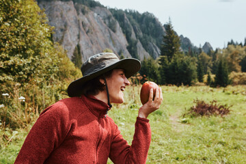 Girl in a hat on nature with a mango in hand.