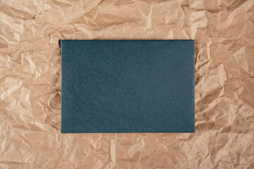 Background image crumpled recycled textured kraft paper with sheet of green cardboard in middle. Top view. Copy space