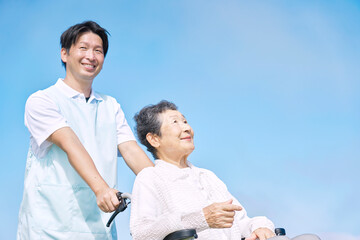 介護士と車椅子に乗る高齢者　屋外