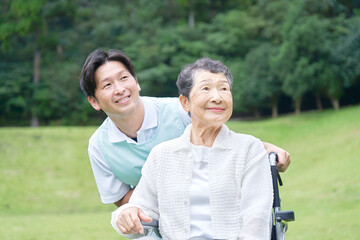 介護士と車椅子に乗る高齢者　屋外