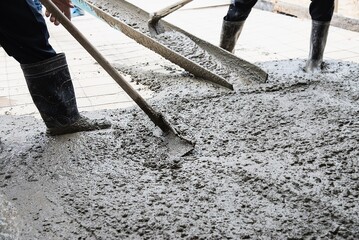 Workman doing floor concrete pouring job in construction site