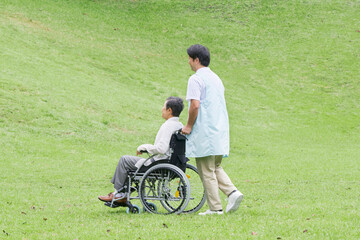 Fototapeta premium 介護士と車椅子に乗る高齢者 屋外