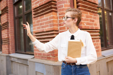 student with glasses walking around the city with a book education