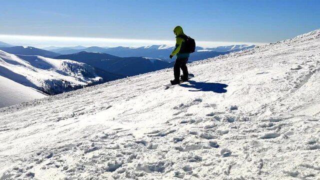 man snowboarder ride by snowed mountains at sunny day