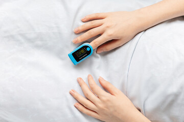 Hand of female patient with a pulse oximeter on the index finger, close-up. A hospitalized patient is in the hospital. Top view