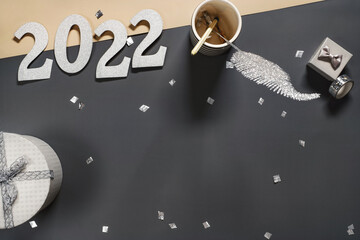 2022 New Year numbers over dark gray background on working table. Copy space for wishes, resolutions, Silver glitter decor with small gifts. Stylish celebration banner