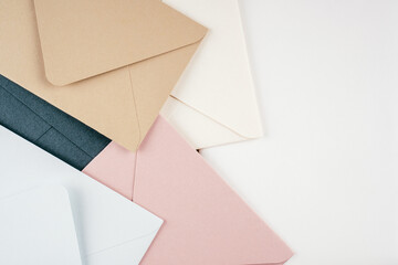 Background image of multi-colored cardboard envelopes lying randomly on white background. Top view, copy space