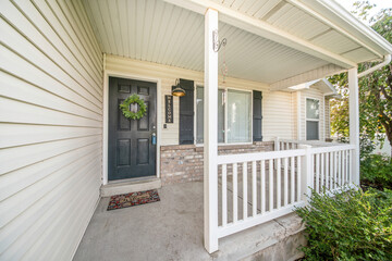 Front porch exterior of a house with bricks and wooden white posts and railings