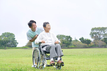 Fototapeta premium 介護士と車椅子に乗る高齢者 屋外