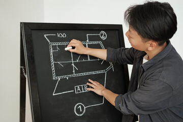 Young coach of engineering drawing sketch on blackboard during presentation of project at seminar or conference