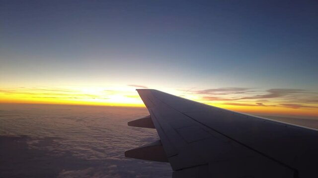 Airplane Flying Over Clouds During Sunrise. POV Passenger Window View.